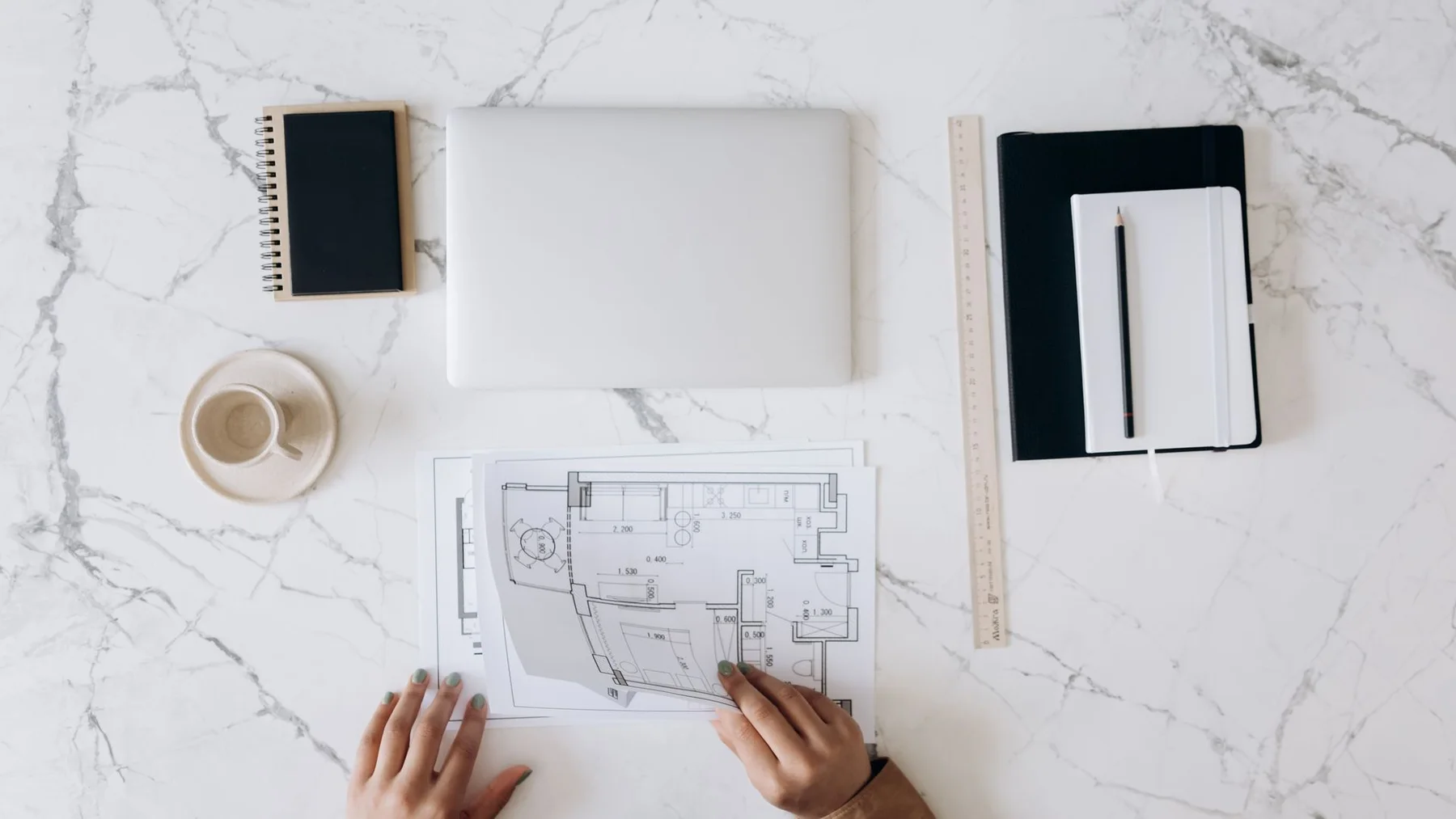 Printed floor plans, a scale ruler and a laptop on an architect's working desk