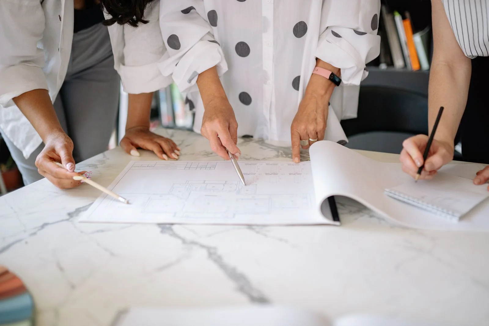 Design professionals measuring and reviewing a printed house plan together